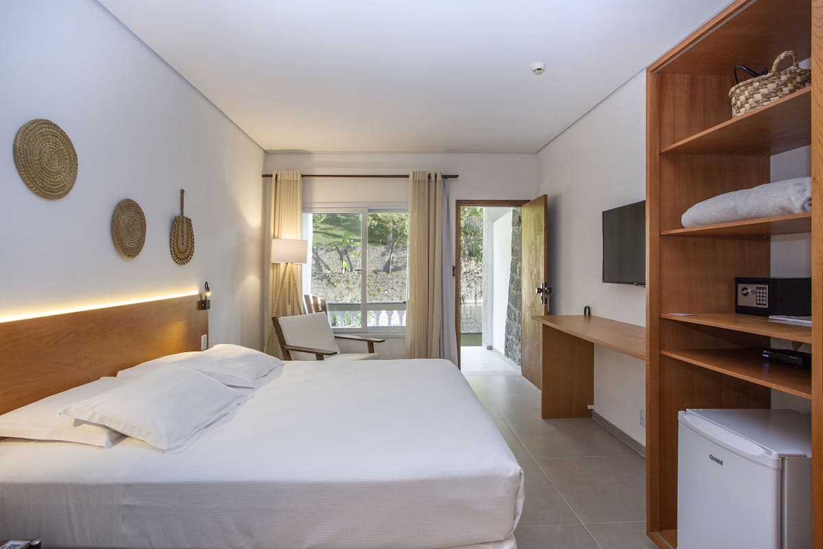 Habitación de hotel con una cama grande, escritorio, televisión y un refrigerador pequeño.