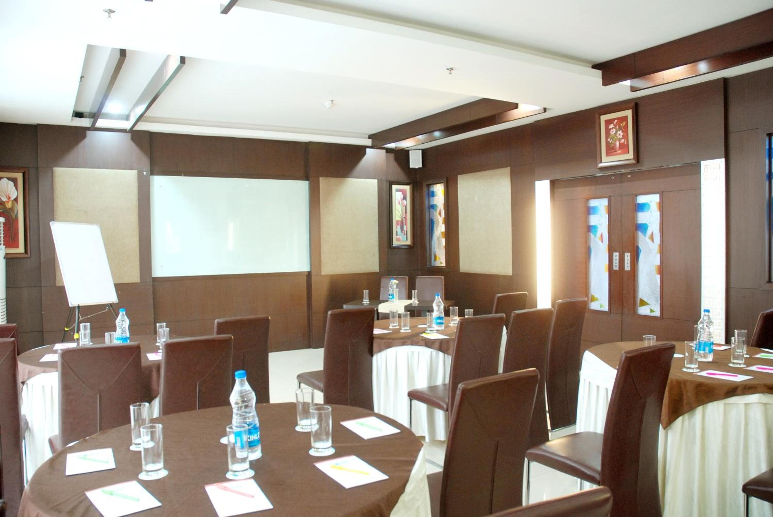 A conference room with round tables, chairs, and a projector screen.