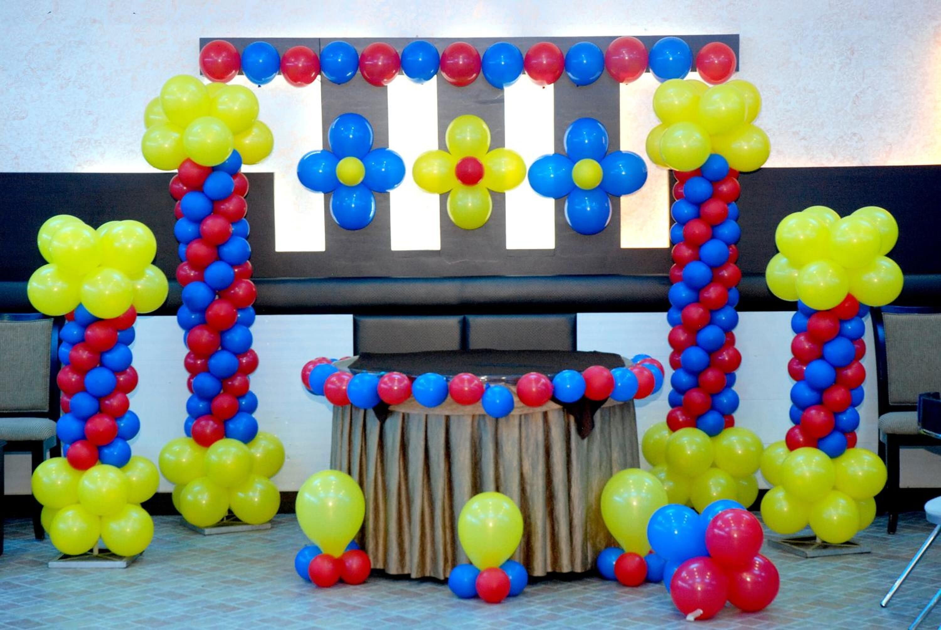 A room with a stage decorated with balloons and a backdrop.