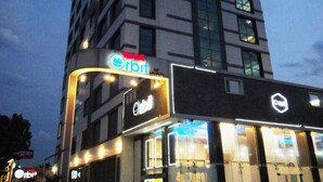 Ein Hotel namens Orbit mit modernem Design, das mehrere Etagen und beleuchtete Fenster zeigt.