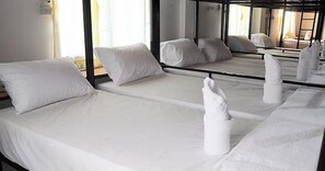 A hotel room with two single beds, each with white linens and pillows, and a large mirror reflecting the room. - Mickey Hostel (Ko Pha-ngan)