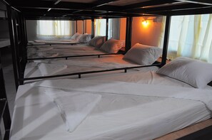 A train compartment with multiple beds arranged in rows, each with a mattress and pillows. - Mickey Hostel (Ko Pha-ngan)