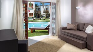 A living room with a sofa, a TV, and a view of a pool and outdoor seating area.