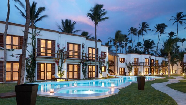 A resort with multiple buildings, a swimming pool, and palm trees.