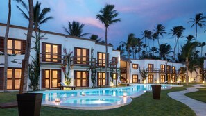 A resort with multiple buildings, a swimming pool, and palm trees.