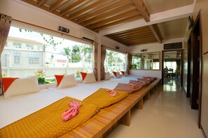 A hotel room with multiple beds, wooden headboards, and large windows with curtains. - Lotus Paradise Resort (Koh Tao)