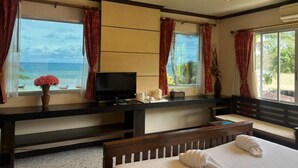 Une chambre d’hôtel avec un lit, une télévision, un bureau et une vue sur l’océan.
