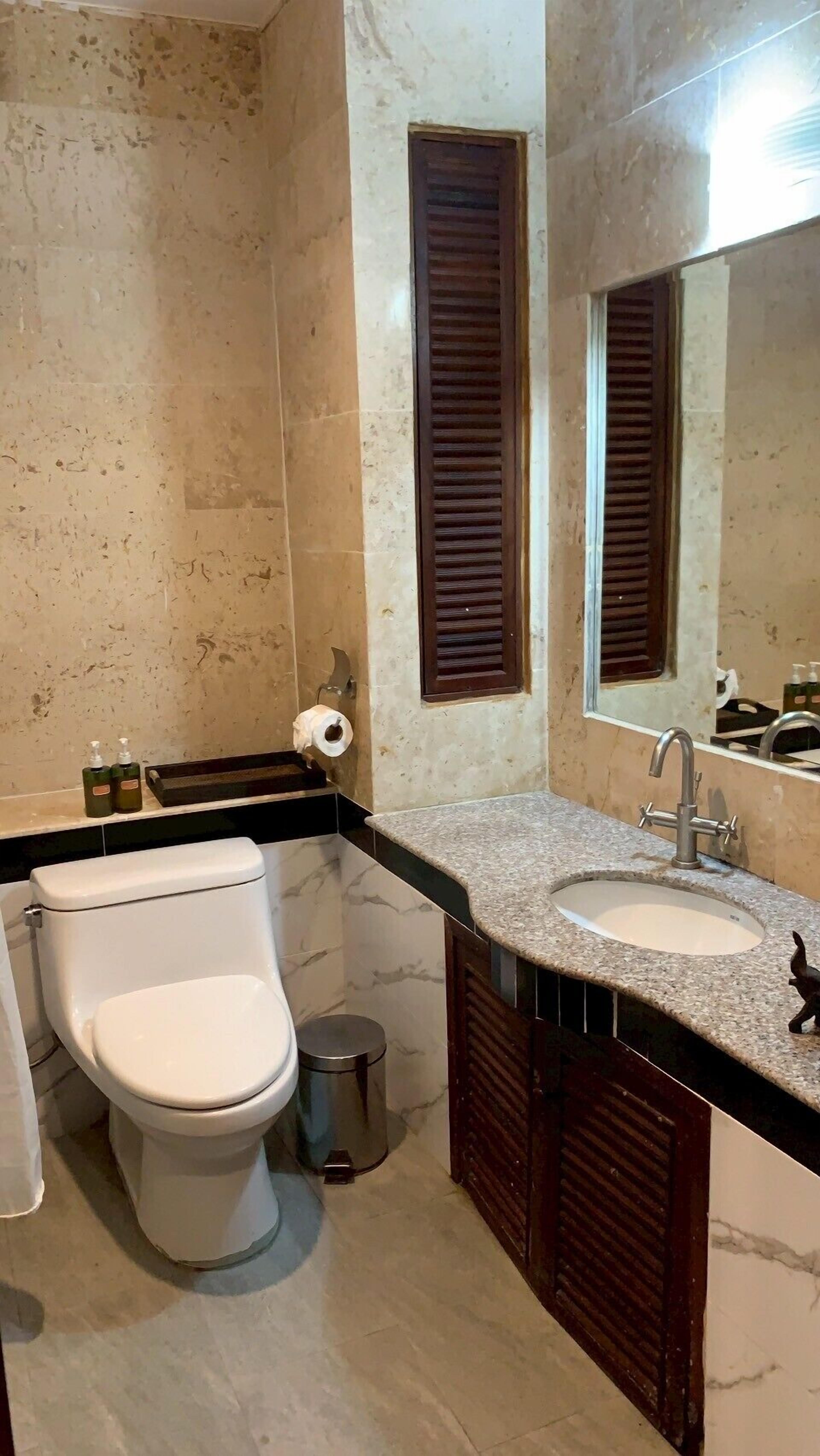A bathroom with a toilet, sink, and mirror.