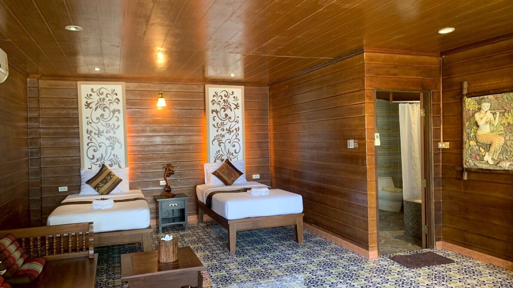 Una habitación con dos camas, techo de madera y piso con diseño.