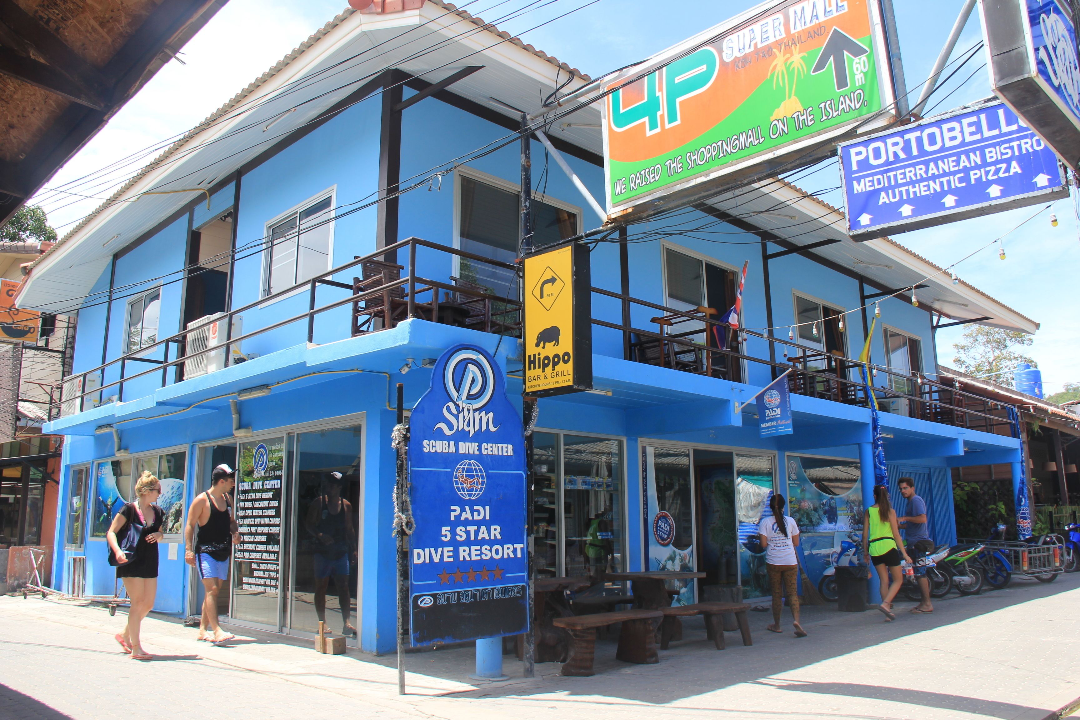 Ein blaues Gebäude mit Schildern für ein Tauchzentrum und eine Bar & Grill.