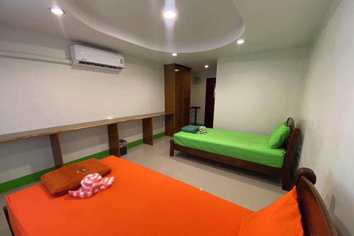Een kleine, compacte kamer met een enkel bed, een bankje en een bureau.
