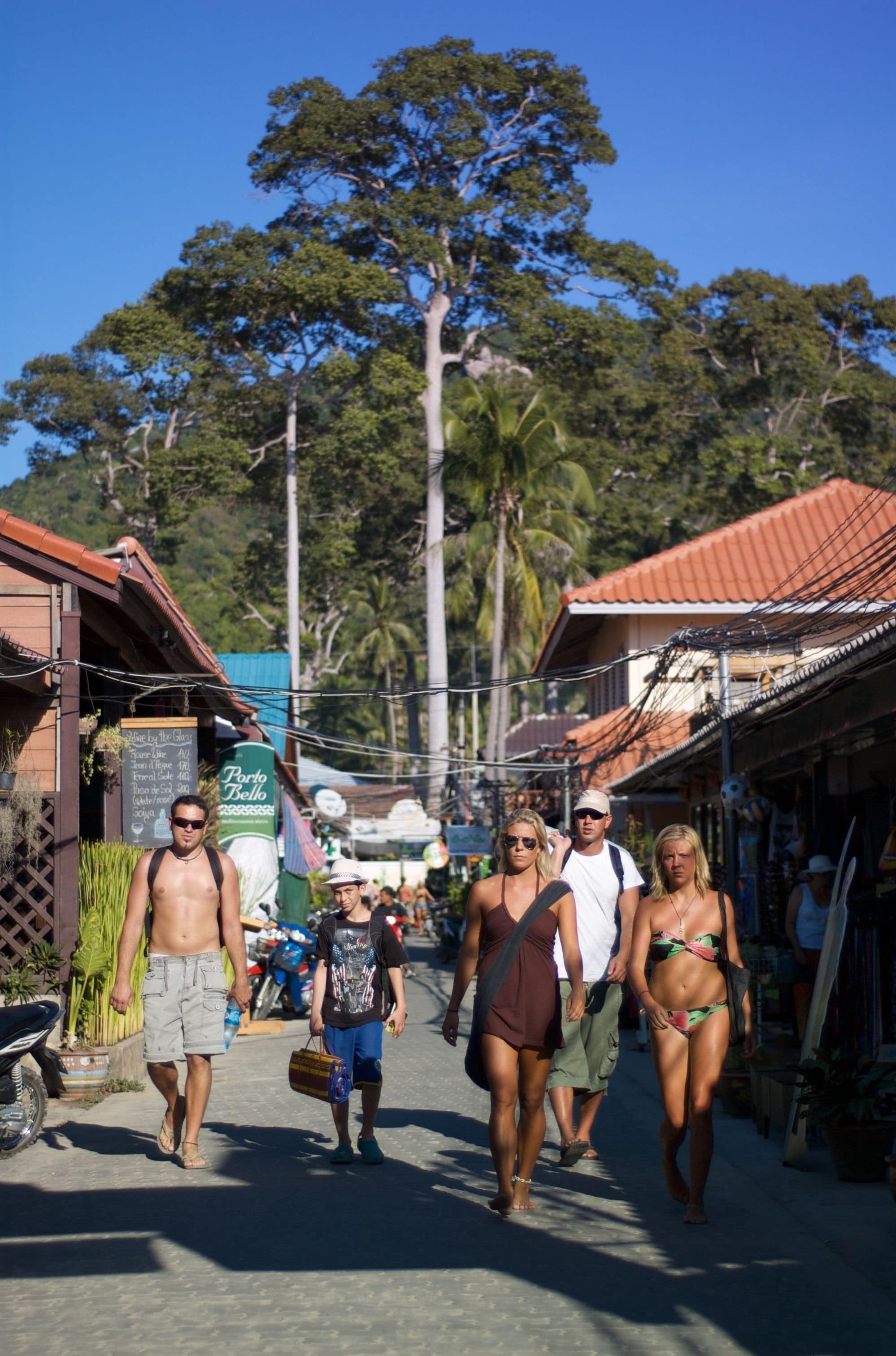 A street scene with people walking, shops, and a sign for 'Parco Bello'.