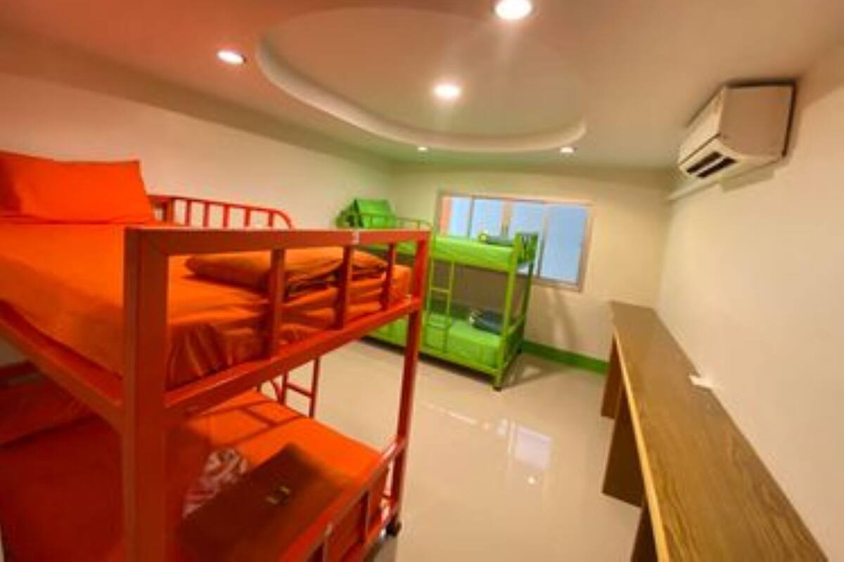 Een kamer met stapelbedden, een raam en een houten bank.