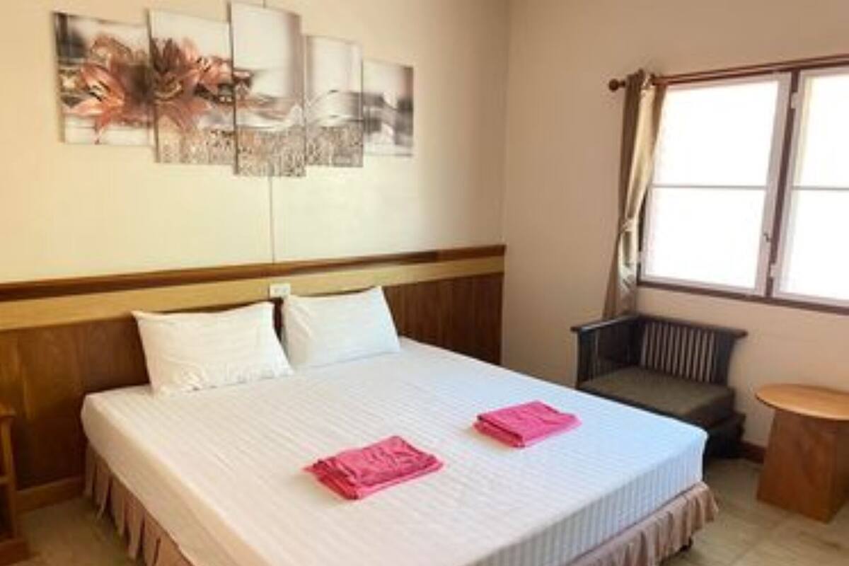 Een hotelkamer met een bed, een stoel, een tafeltje en een raam met gordijnen.