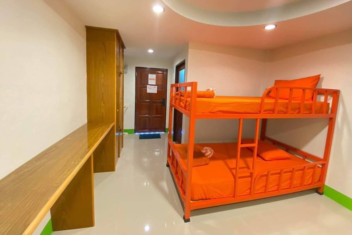Een slaapkamer met een stapelbed, een houten bankje en een deur op de achtergrond.