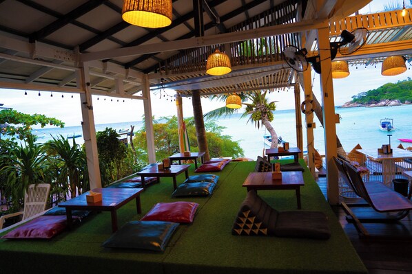 An outdoor seating area with tables and chairs, overlooking a body of water.