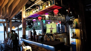A bar area with a wooden counter, shelves with bottles, and jellyfish decorations. - JP Resort Koh Tao (Koh Tao)