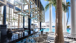 A bar area with wicker chairs, a pool, and palm trees. - Hotel Guayarmina Princess - Adults Only (+16) (Adeje)