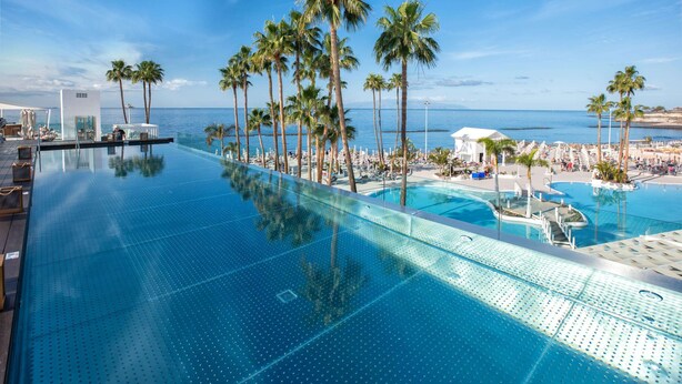 A infinity pool with palm trees and a view of the ocean. - Hotel Guayarmina Princess - Adults Only (+16) (Adeje)