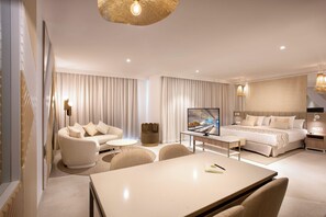 Une chambre d’hôtel moderne équipée d’un canapé, d’une table à manger, d’un téléviseur et d’un lit.