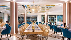 A spacious dining area with a long table set for a meal, surrounded by wicker chairs and blue upholstered chairs. - Hotel Guayarmina Princess - Adults Only (+16) (Adeje)