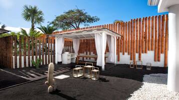 A patio area with a wooden fence, a covered seating area, and a cactus plant.