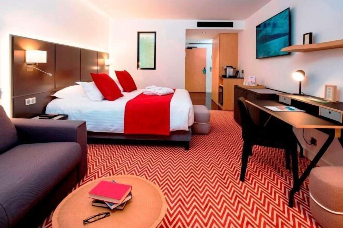 A hotel room with a bed, desk, and seating area.