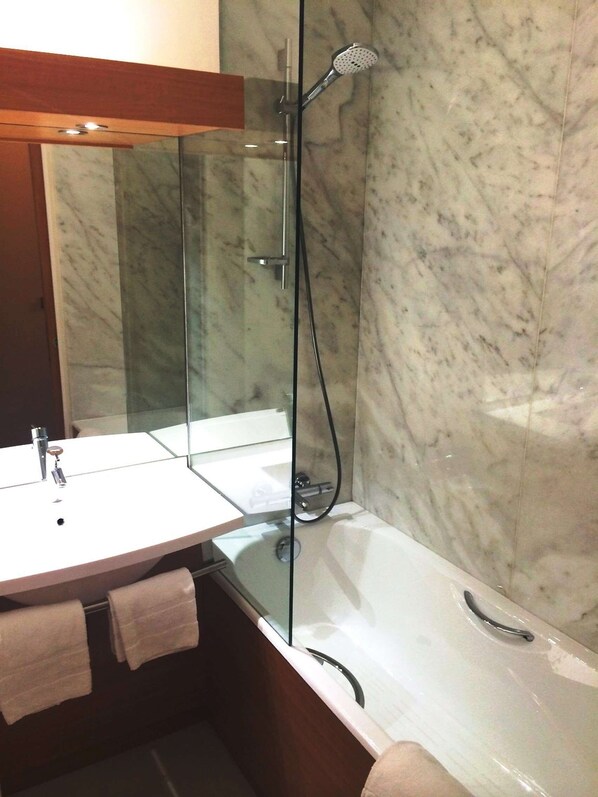 Un baño con ducha de vidrio, lavamanos blanco y bañera.