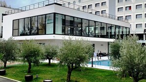 Een modern gebouw met een glazen gevel, een dakterras en een zwembad.