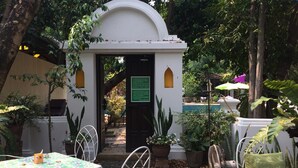 Un patio con un arco blanco, mesas con manteles florales y sillas.
