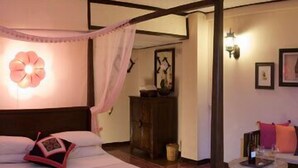 Una habitación con una cama, una mesita pequeña y una lámpara fijada en la pared.