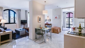 Ein modernes Hotelzimmer mit Essbereich, einer Couch, einem Fernseher und Blick auf die Stadt.