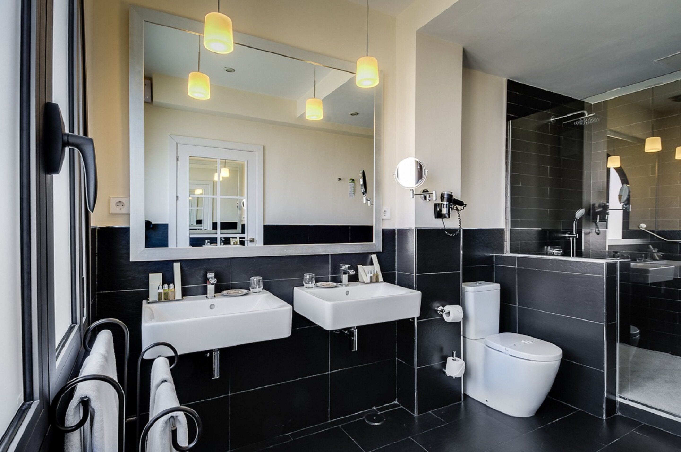 A modern bathroom with two sinks, a toilet, and a glass shower enclosure.