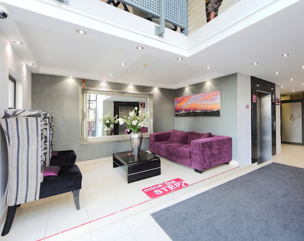 Eine moderne Lobby mit einem violetten Sofa, einem großen Spiegel und einem Stadtbild.