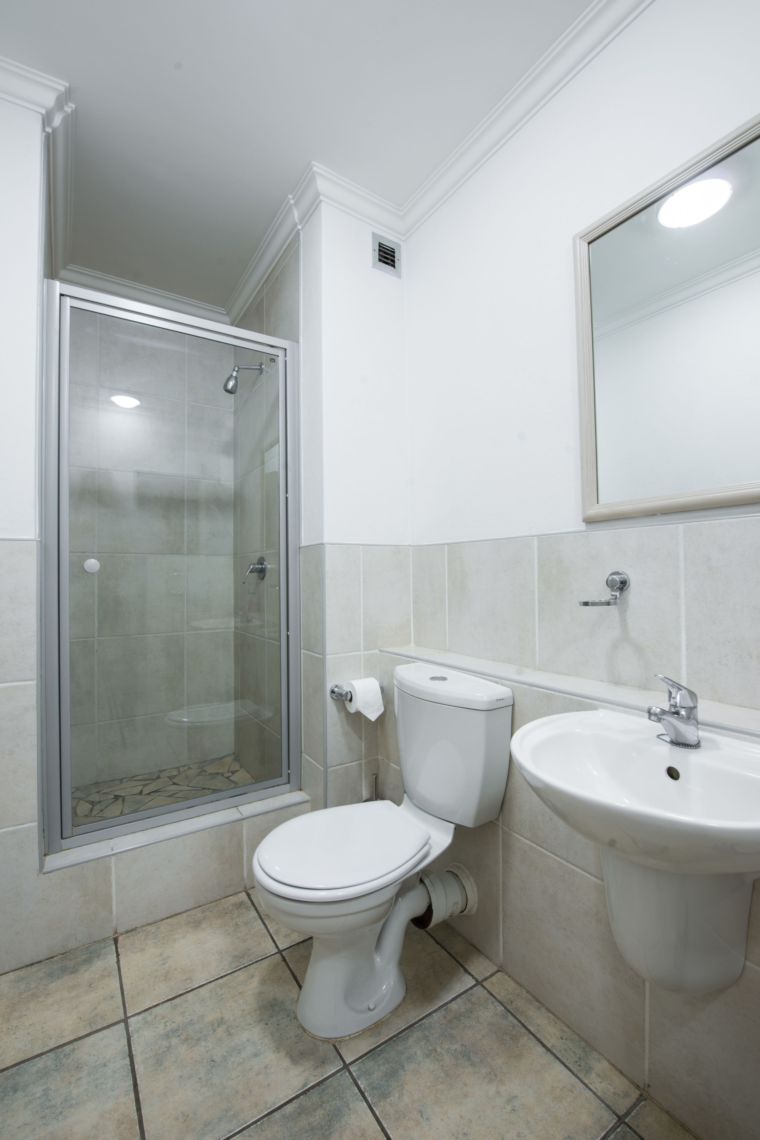 A bathroom with a toilet, sink, and glass-enclosed shower.