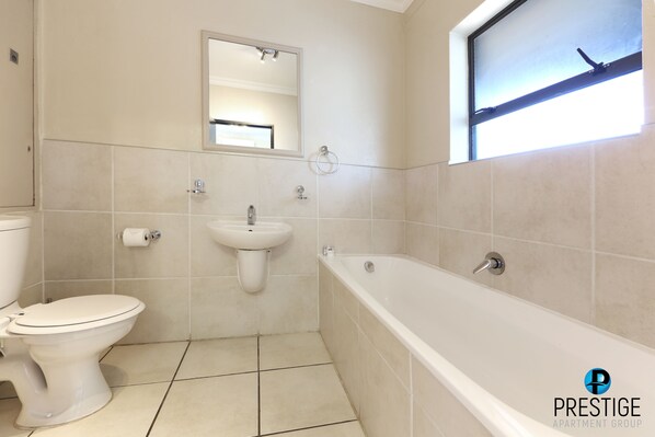 A bathroom with a toilet, sink, and bathtub.