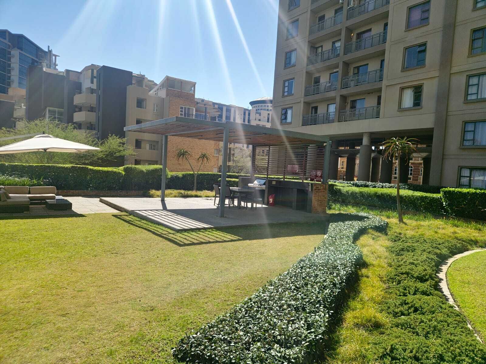Un patio con zona de estar cubierta, un sendero y setos bien cuidados.
