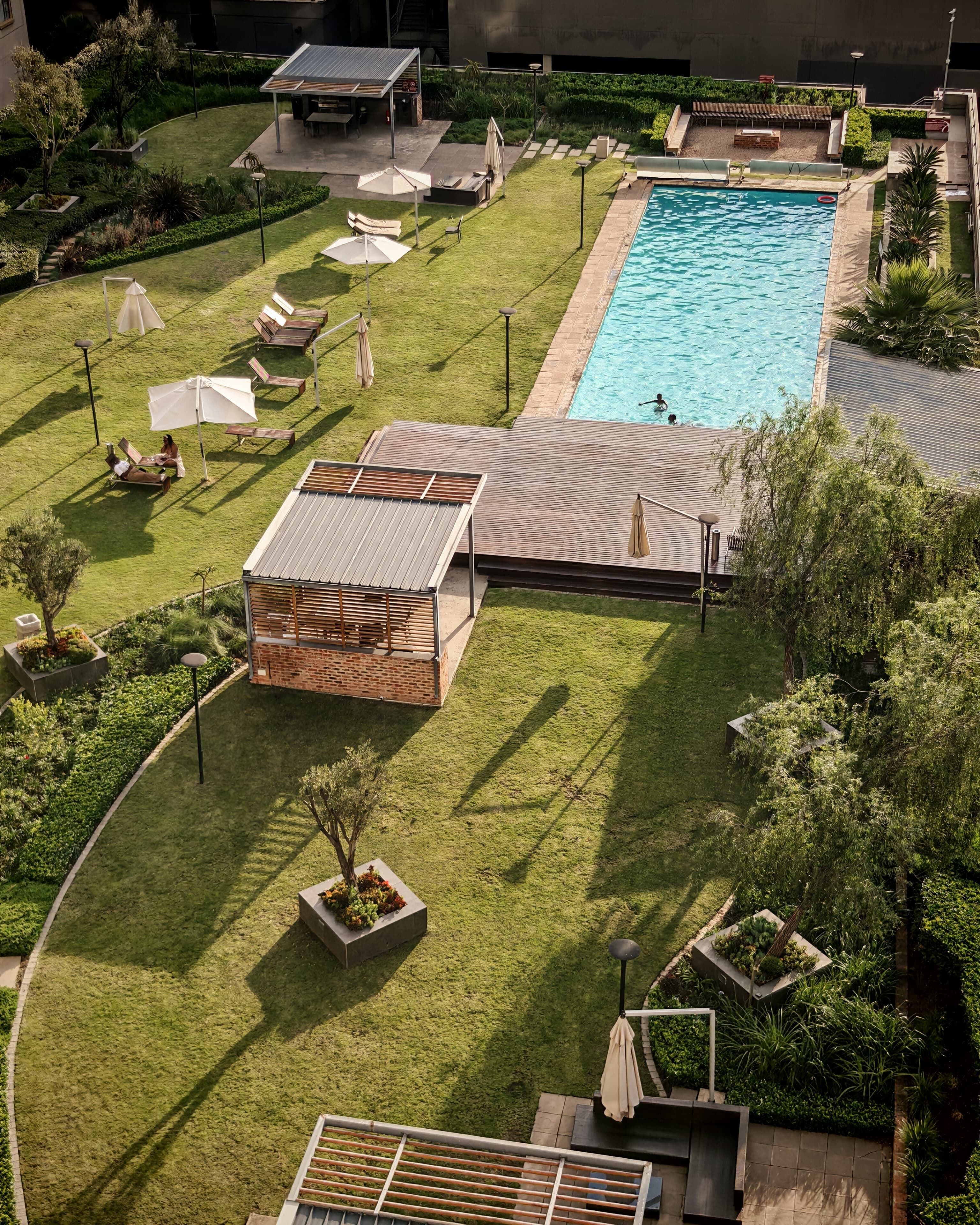 Ein Luftbild eines Resorts mit Schwimmbad, Liegestühlen und einer überdachten Sitzgelegenheit.