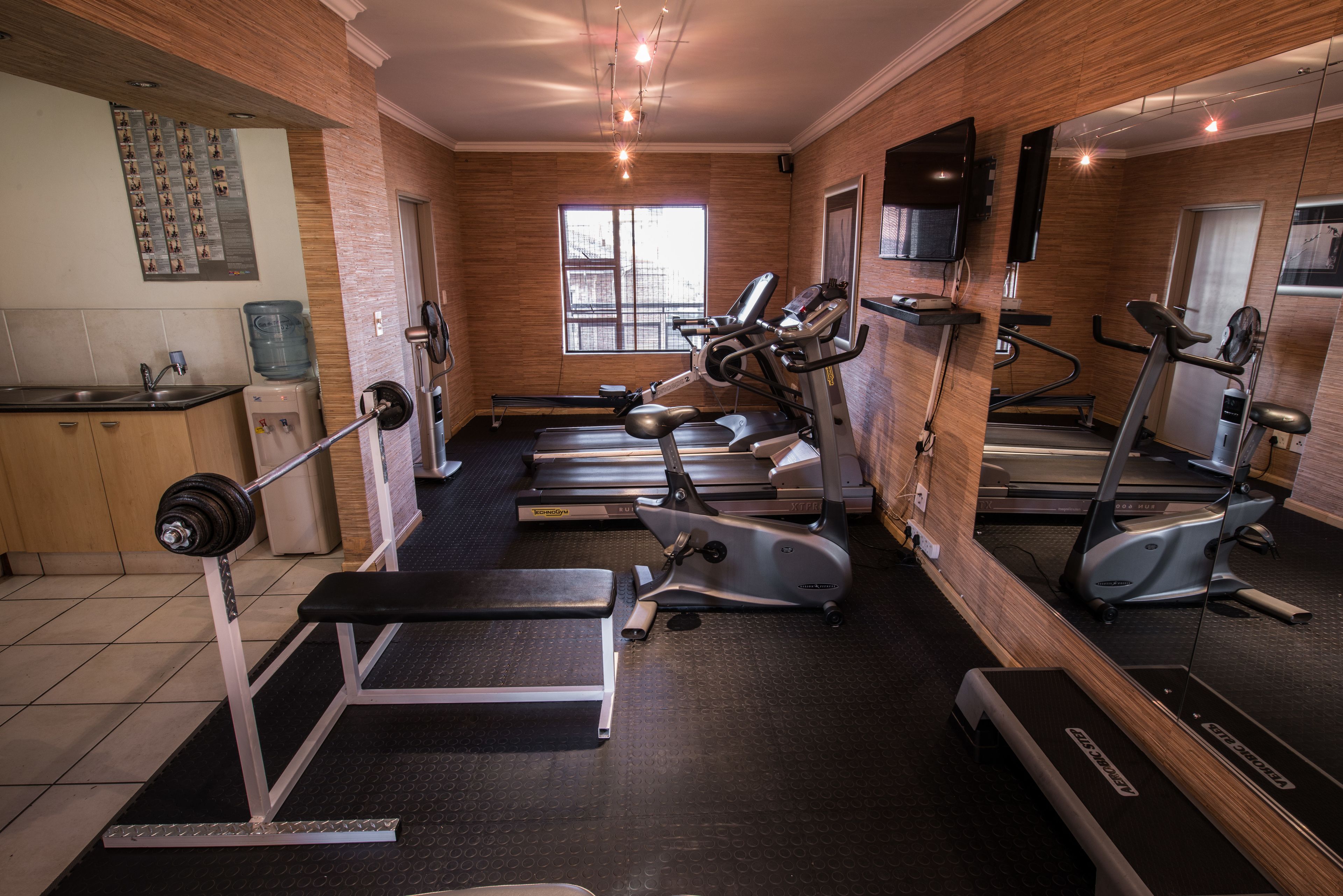 A gym with treadmills, elliptical machines, and a weight bench.