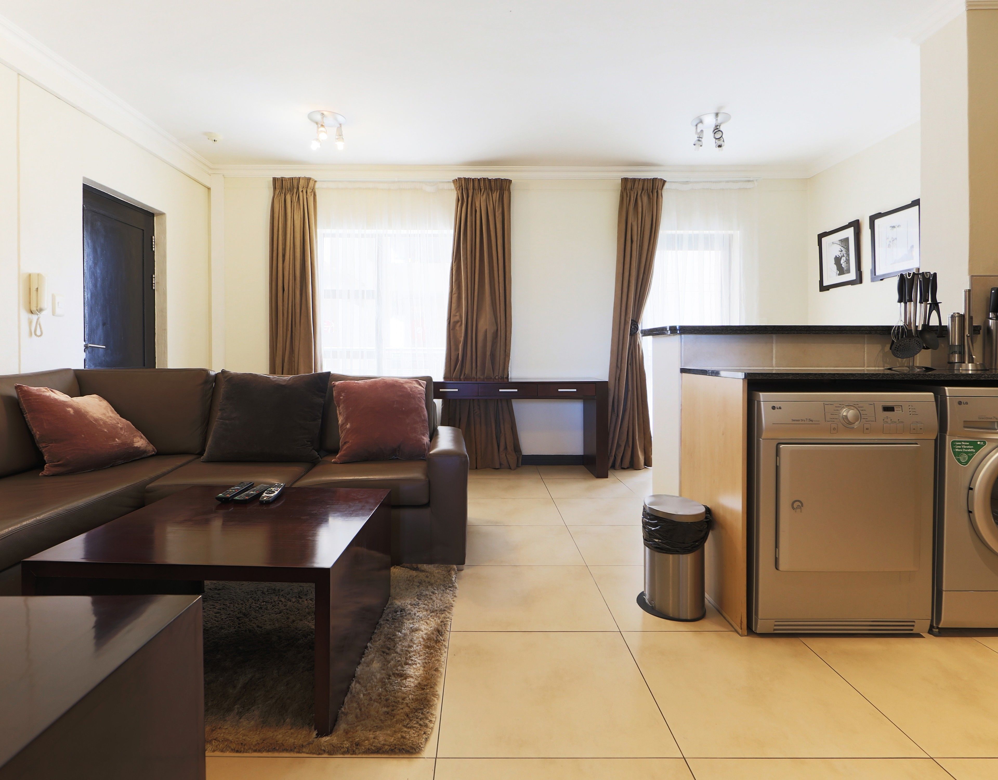 A living room with a sofa, coffee table, and a kitchen area with a washing machine.