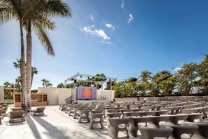 An outdoor seating area with chairs and a stage for presentations, surrounded by palm trees and a clear sky. - Hotel Tabaiba Princess- All Inclusive (San Bartolomé de Tirajana)
