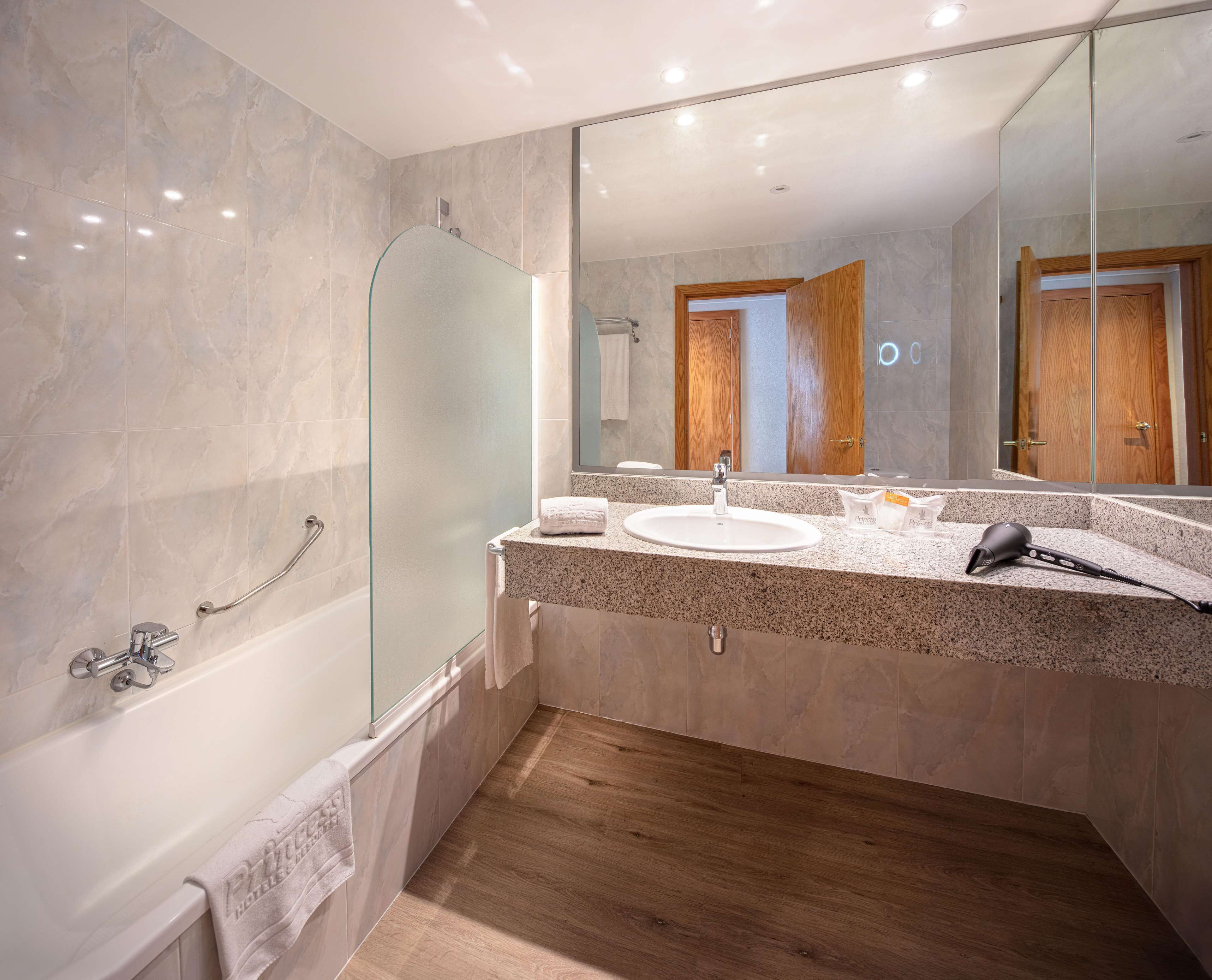 A modern bathroom with a glass shower enclosure, a sink with a vanity, and a large mirror.