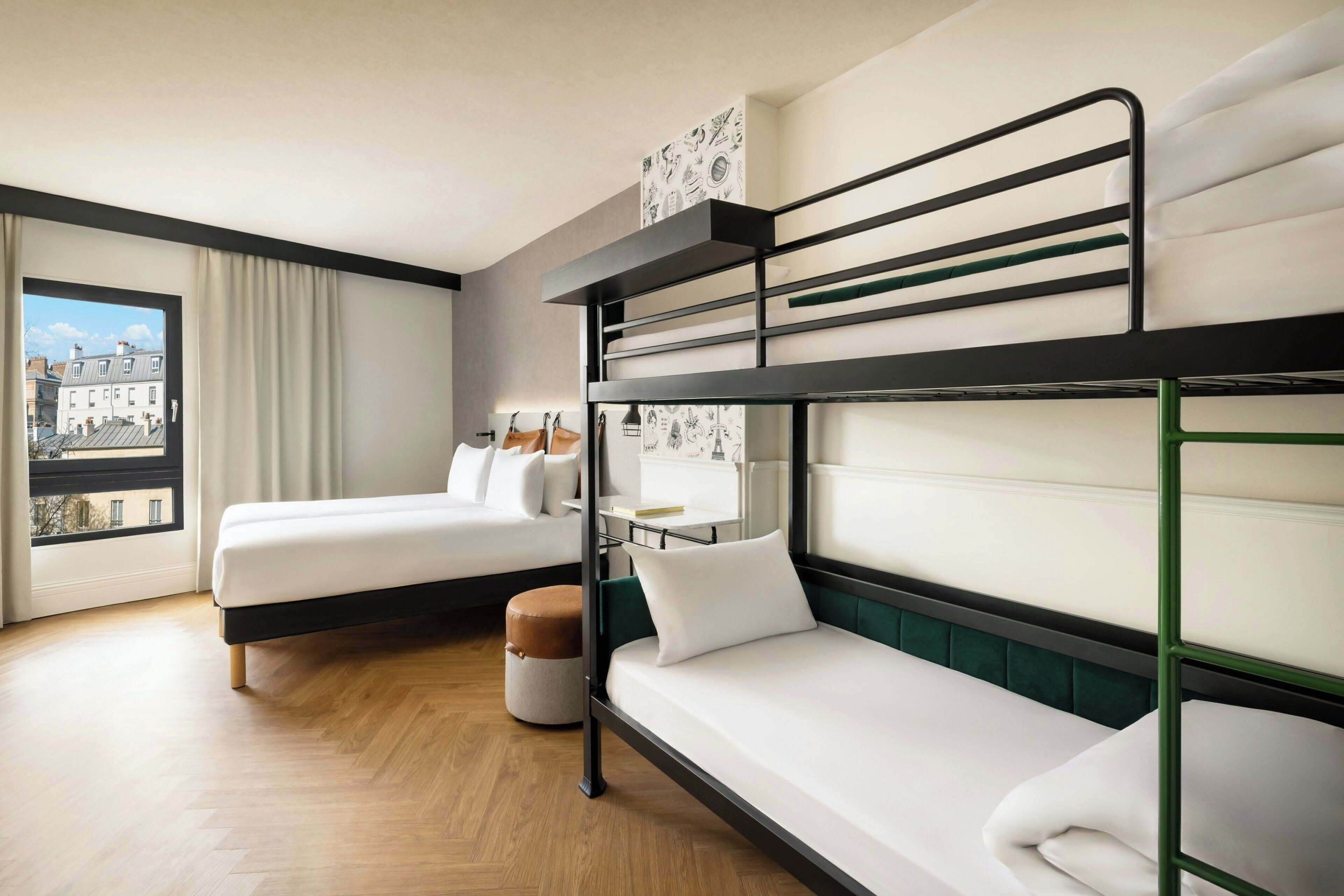 Habitación de hotel con dos camas, una ventana con vistas y una pequeña mesa con una silla.