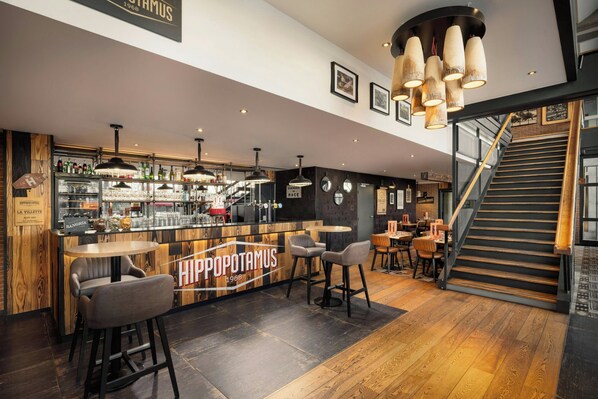 A bar area with stools, a counter, and a staircase leading to an upper level.
