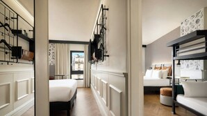 A hotel room with a bed, a sofa, a window with a view, and a wall-mounted shelf. - Moxy Paris La Villette (Paris)