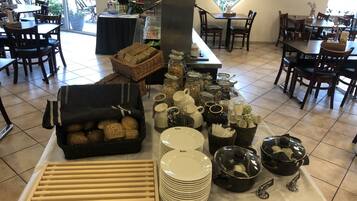 A buffet setup with various food items, utensils, and dishes.