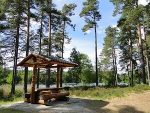 A wooden gazebo with benches in a forested area near a body of water. - Rasta Eksjö (Eksjo)