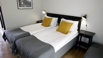 A neatly made bed with two pillows, a bedside table with a lamp, and a framed picture on the wall.