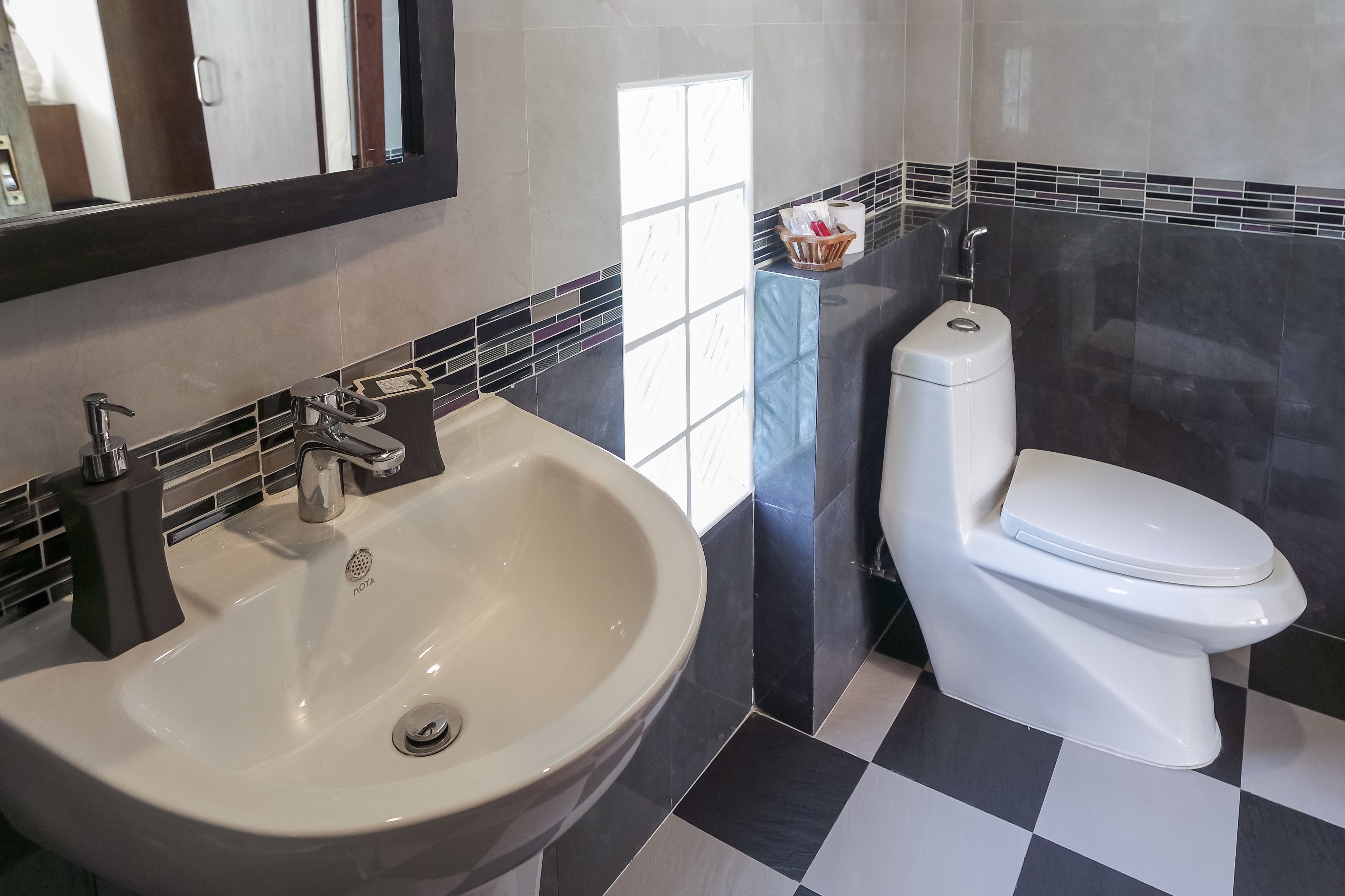 A bathroom with a white sink, a toilet, and a mirror.