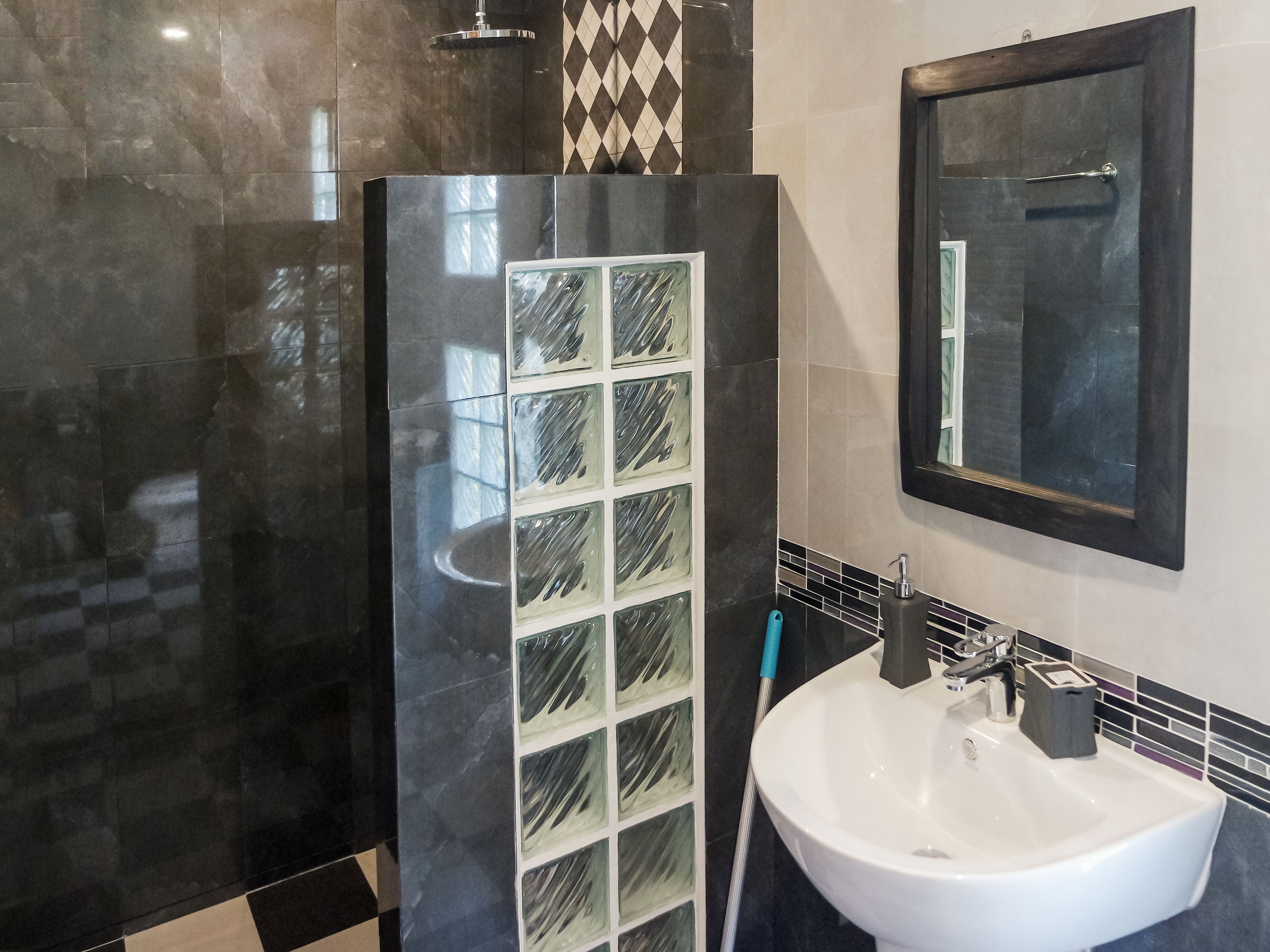 A modern bathroom with a glass shower enclosure, a white sink, and a mirror above it.